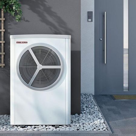 Eine weiße Klimaanlage mit Heizfunktion steht vor einem Haus