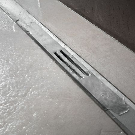 Metallgitter mit Wasserabfluss in der Dusche auf dem Boden